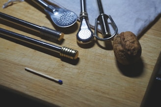 Set of reusable metal straws with cleaning brushes on a rustic surface.