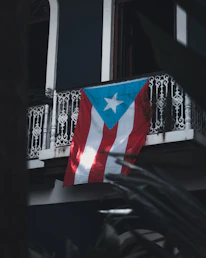 Close-up of hands signing a legal contract with a Puerto Rico flag in the background.