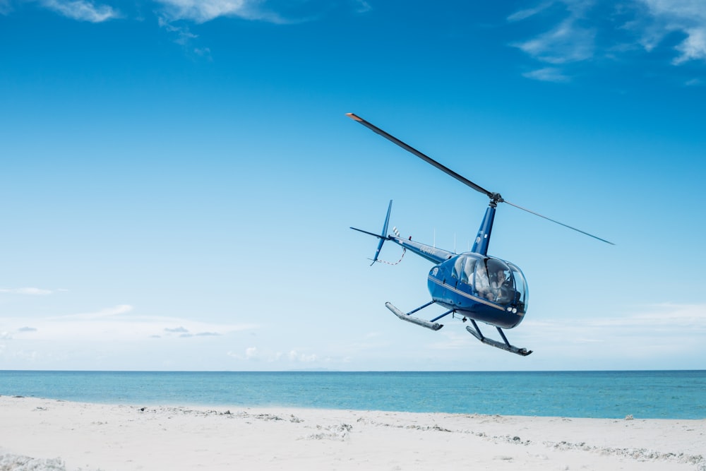 Blauer Hubschrauber fliegt am Strand