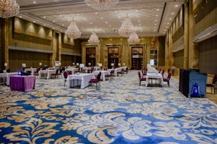 A formal event setup features tables adorned with elegant decorations including white flowers, glass