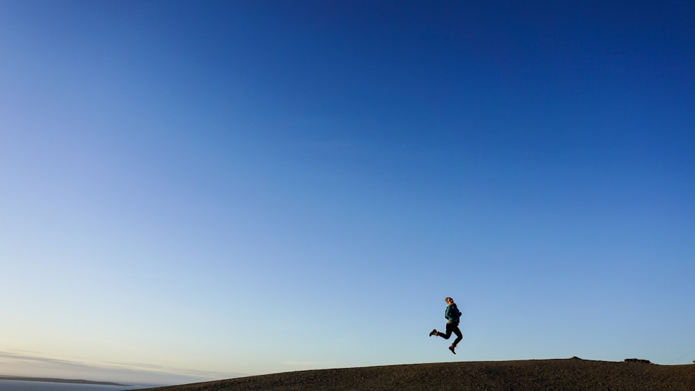 person jumping on hill