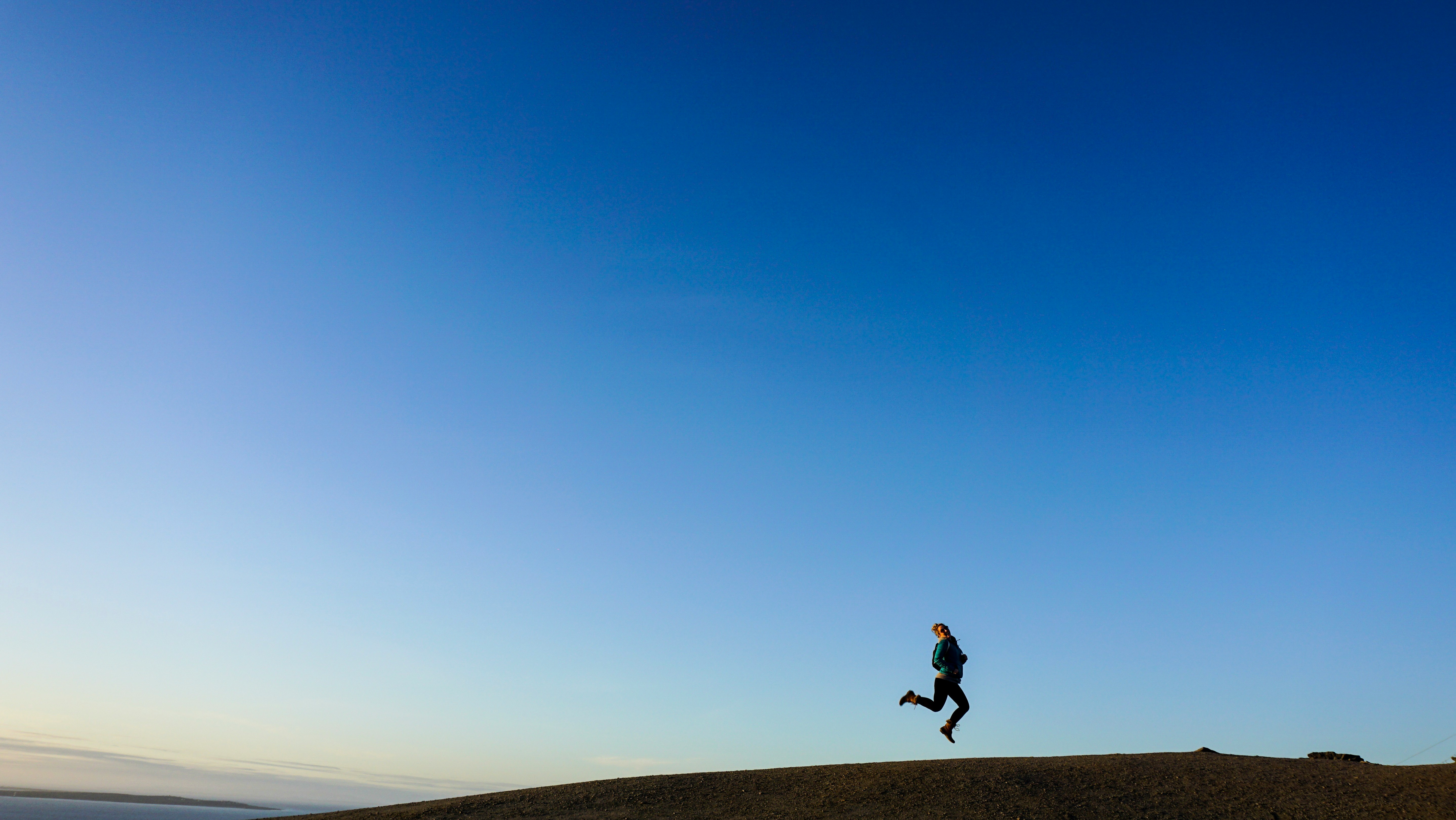 person jumping on hill