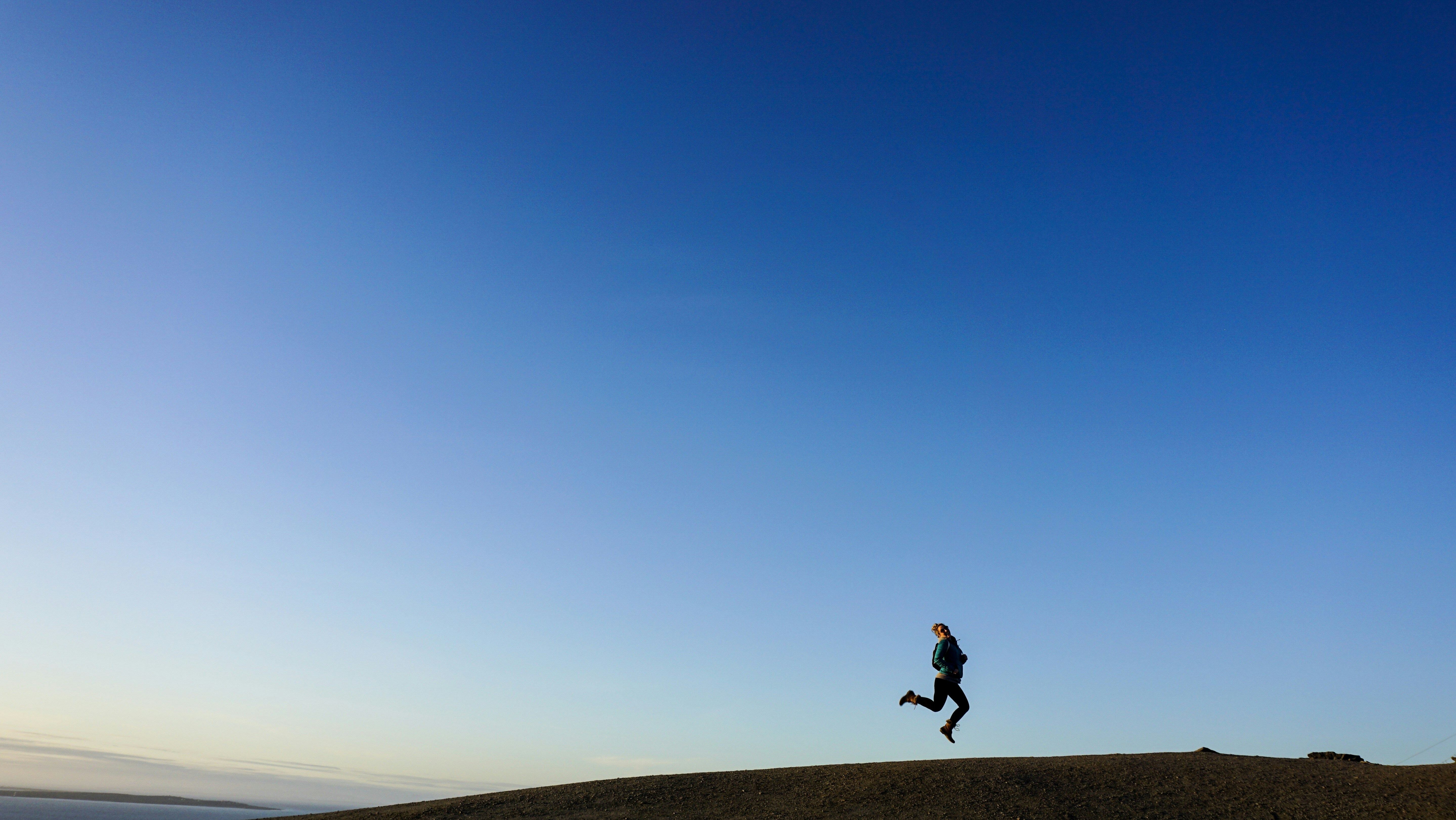 person jumping on hill