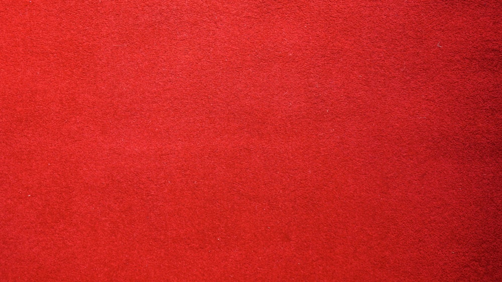 Una alfombra roja con un gato negro encima