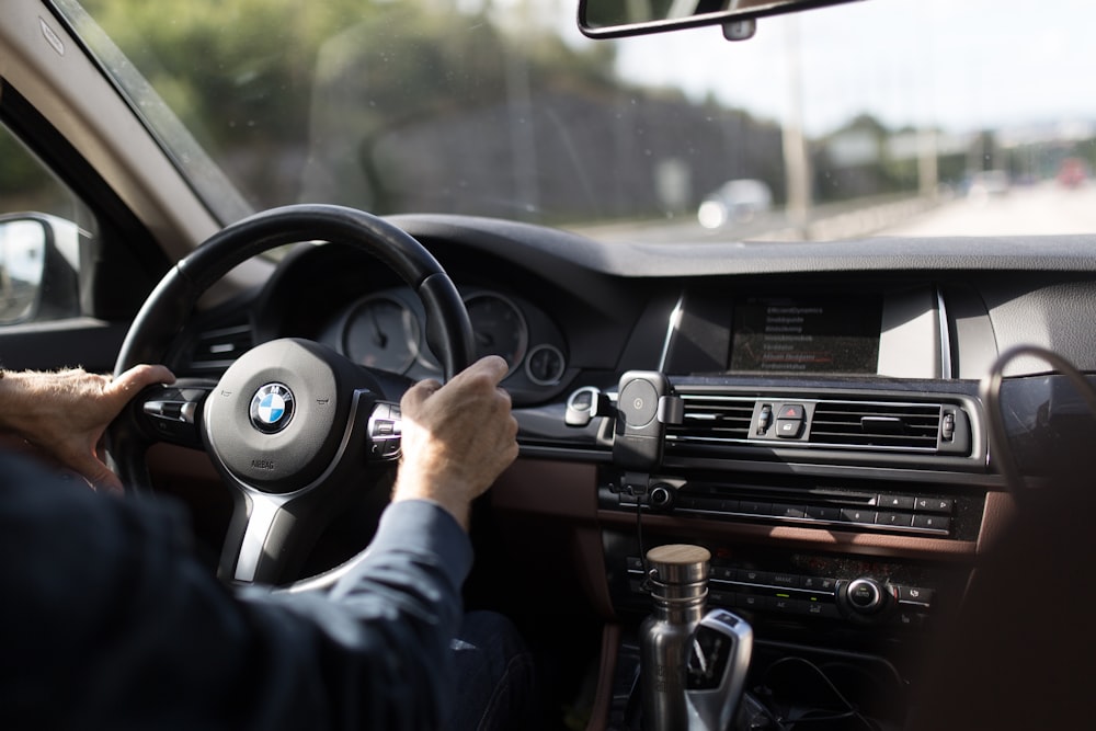 person holding BMW steering wheel