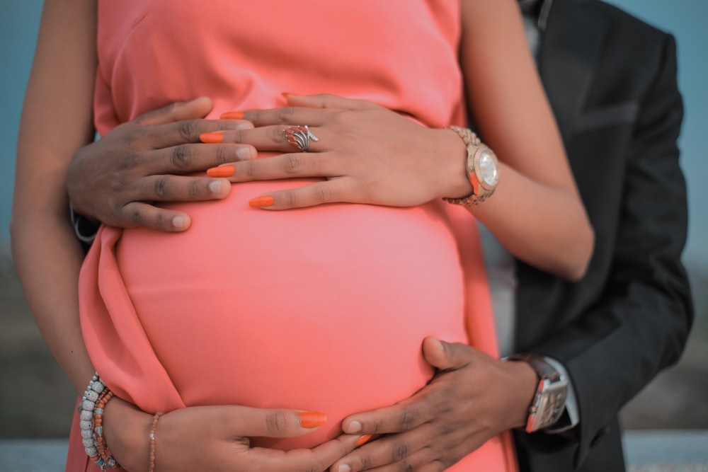 man standing at the back of pregnant woman while touching her tummy