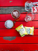A close-up of a wooden table topped with a frothy pint and a plate of pub snacks