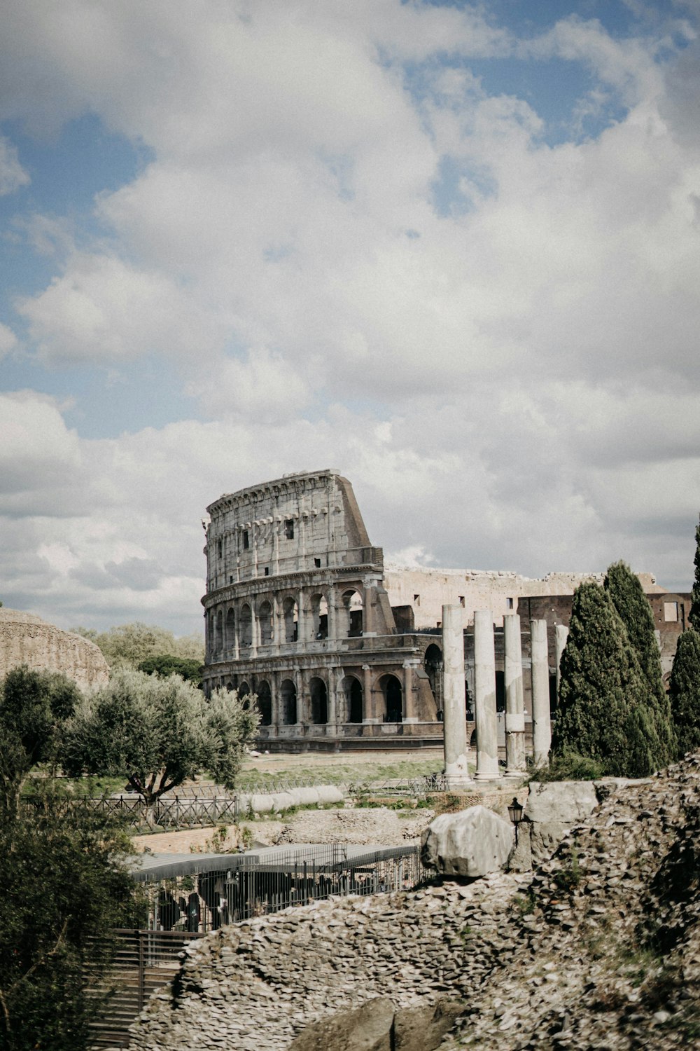 personas de pie cerca del Coliseo en Roma, Italia, bajo cielos blancos y azules durante el día