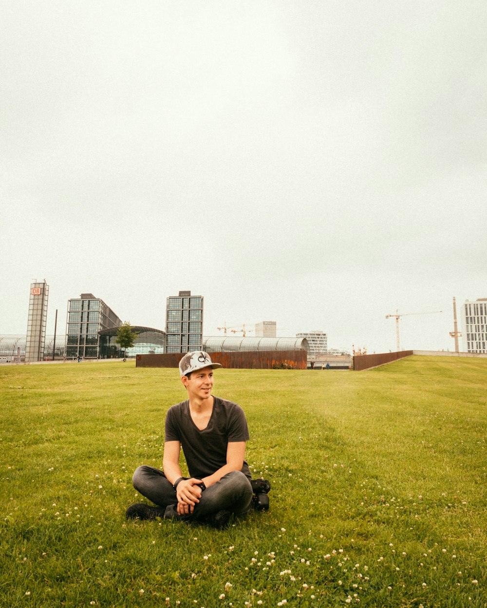 man wearing black crew-neck t-shirt sitting on grass during daytime