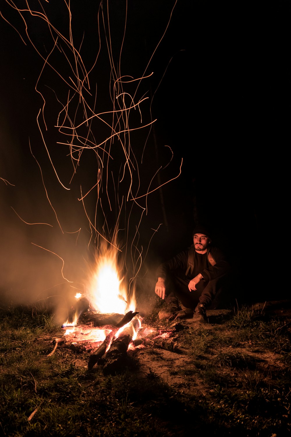 man sitting beside bonfire