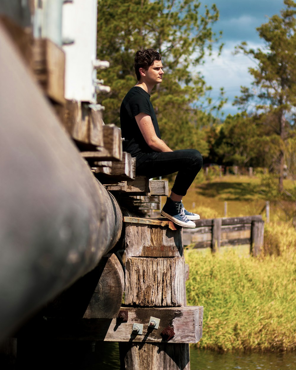 selective focus photography of man in black shirt sitting outdoor during daytime