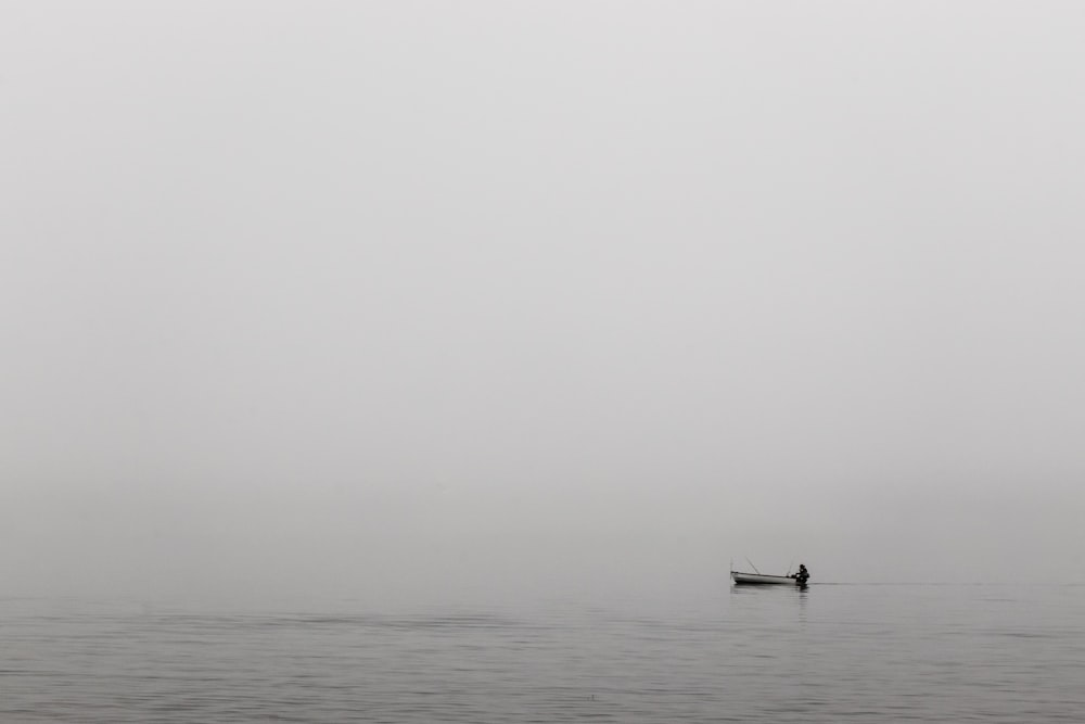 person sitting on white boat on ocean water