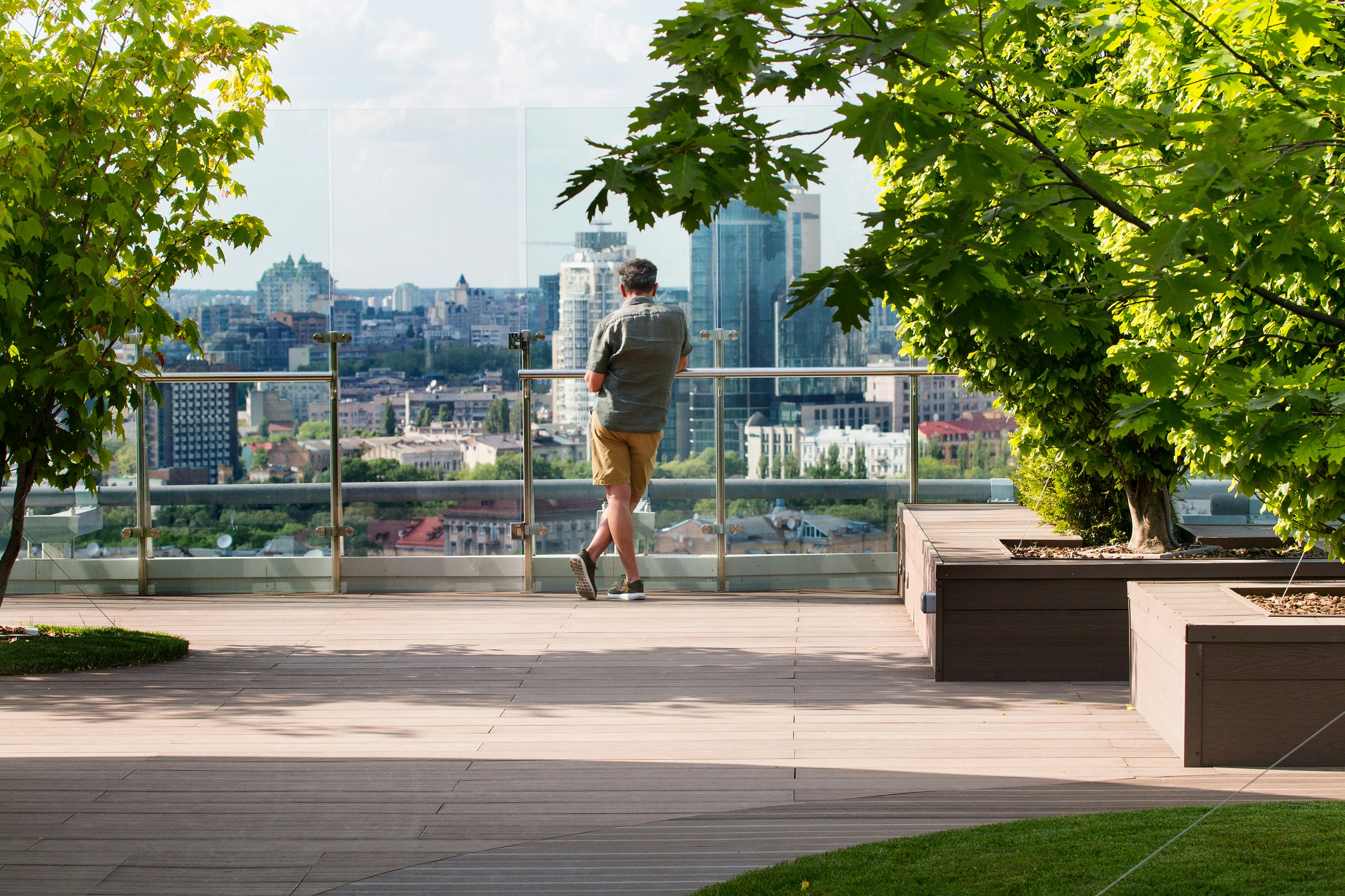 person in gray shirt and yellow shorts, man looks at the city from the roof