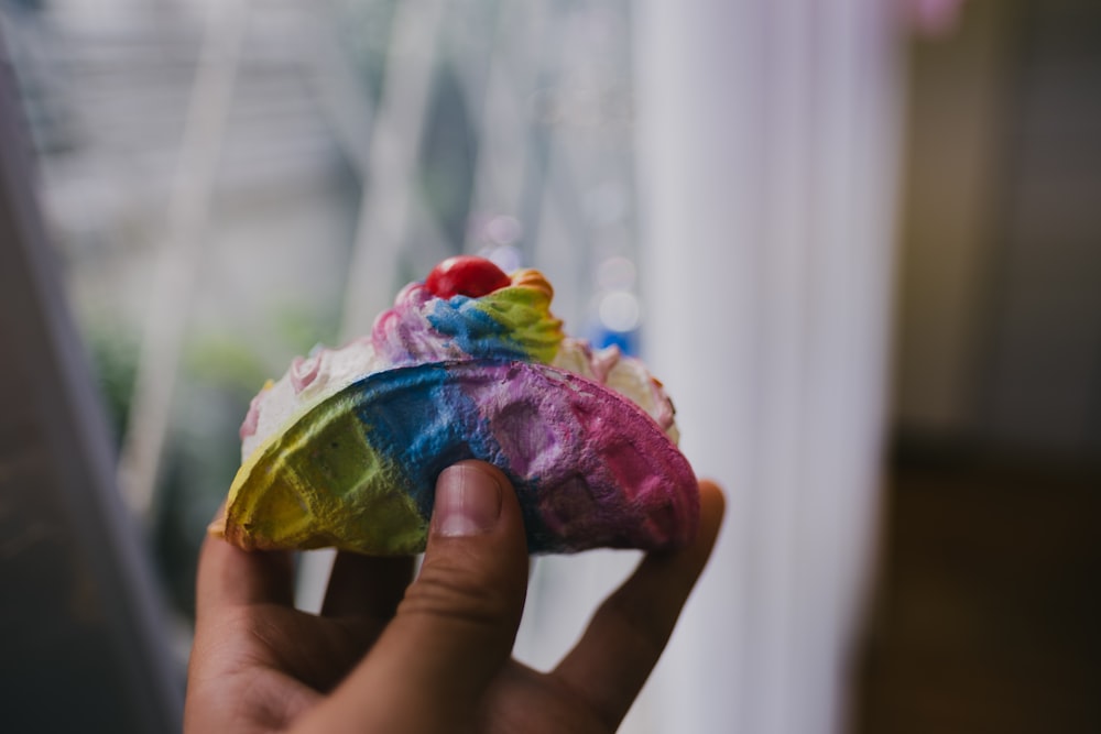 a person holding a colorful pastry in their hand