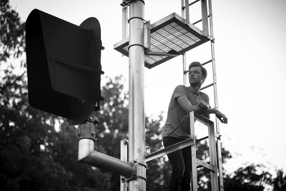 grayscale photography of man standing on tower