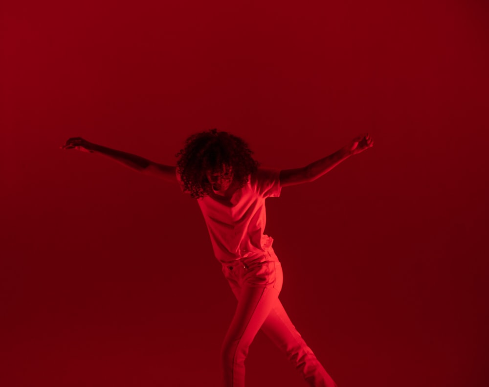 photography of woman dancing near red background