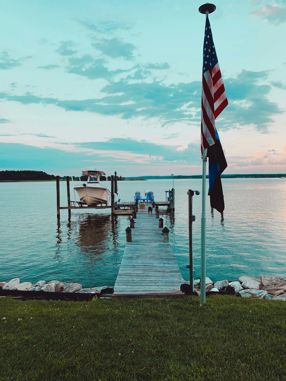 American flag near gray wooden beach dock viewing blue sea under blue skies during daytime