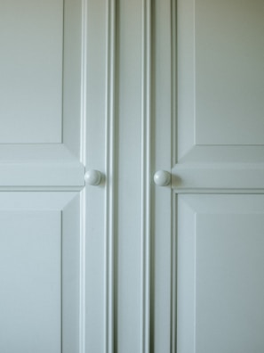 Close-up of smooth cabinet surfaces painted in a warm cream color with modern hardware.