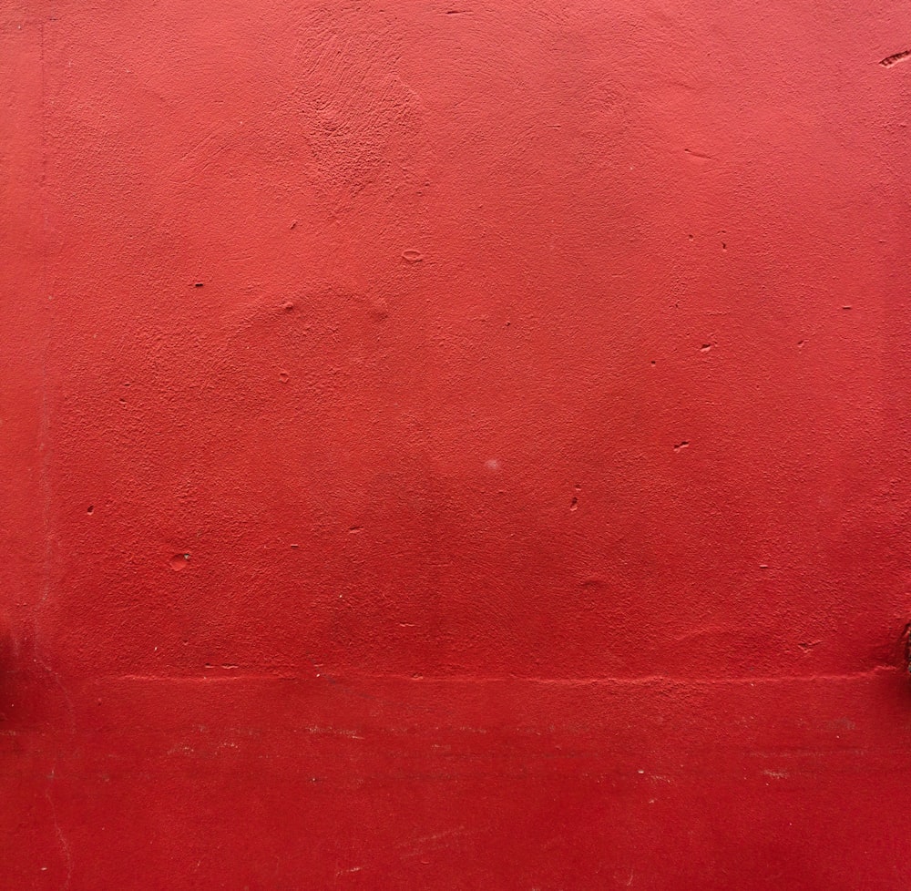 uma parede vermelha com um hidrante sobre ela