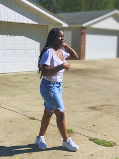 A model wearing casual denim shorts walking outdoors on a sunny day.