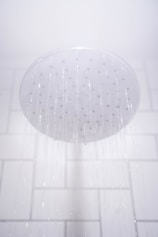 water from round gray stainless steel shower head