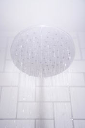 water from round gray stainless steel shower head