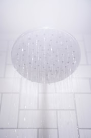 water from round gray stainless steel shower head