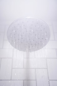 water from round gray stainless steel shower head