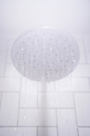 water from round gray stainless steel shower head