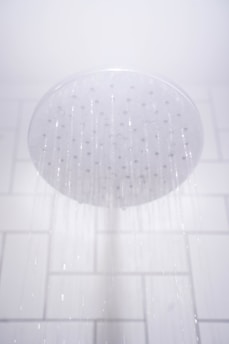 water from round gray stainless steel shower head