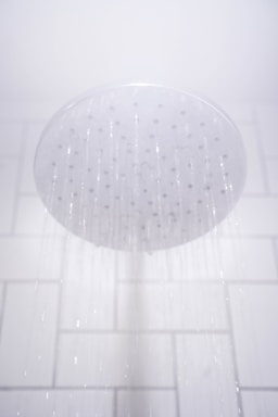 water from round gray stainless steel shower head