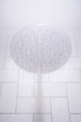 water from round gray stainless steel shower head