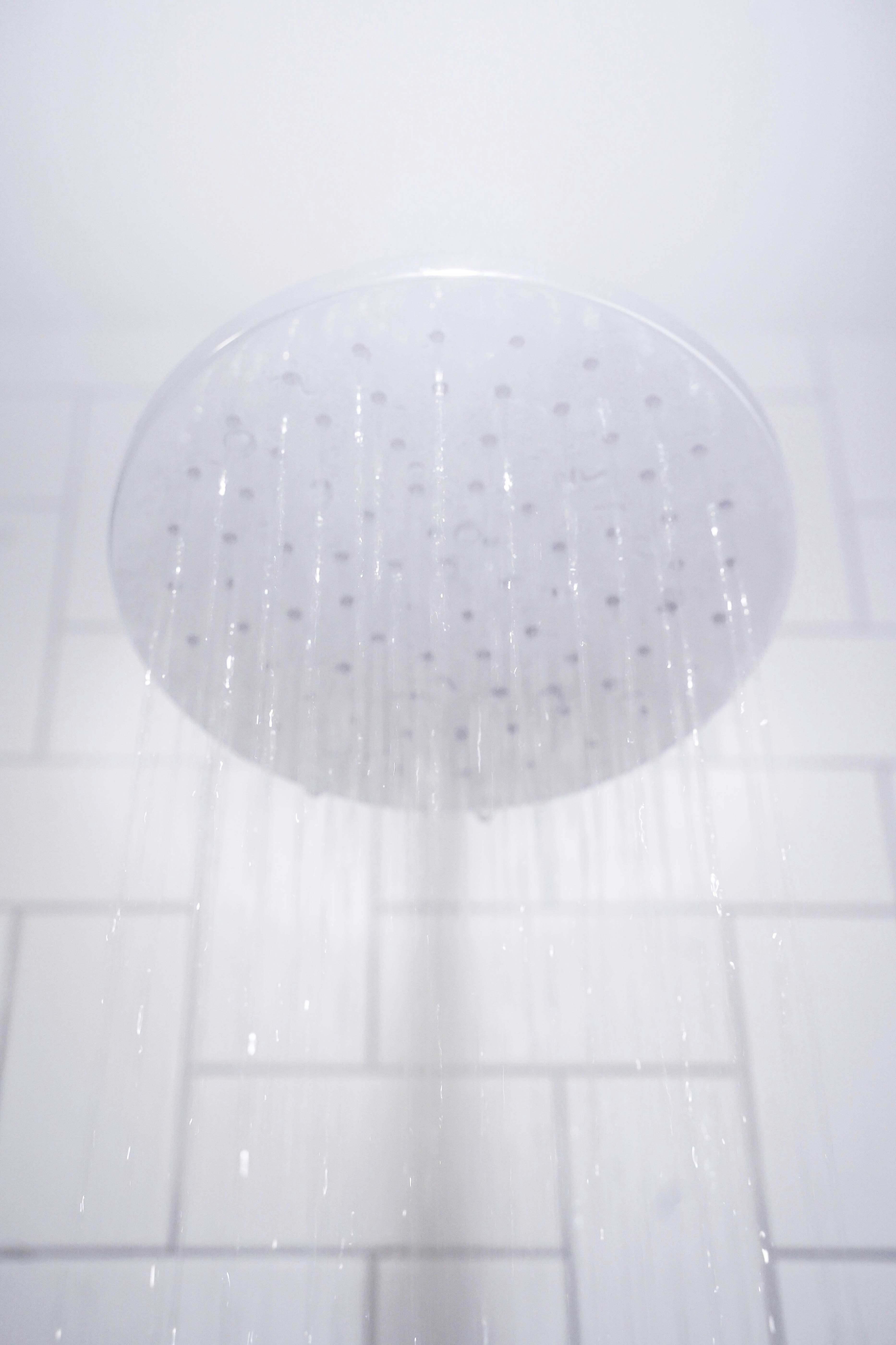 water from round gray stainless steel shower head