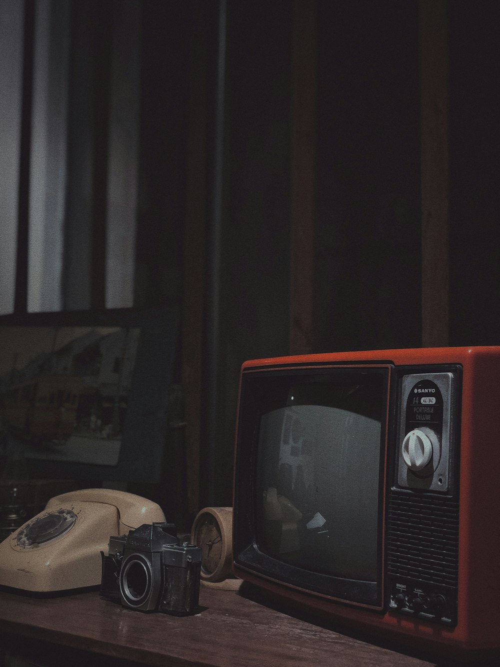 CRT television, camera, clock and rotary telephone on sideboard