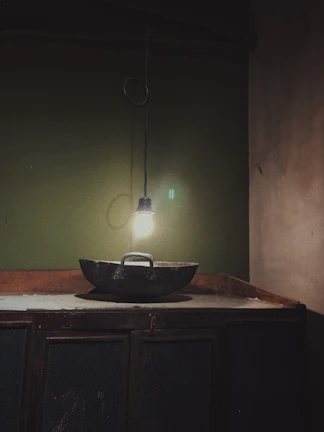 Rustic iron chandelier casting soft shadows above a rustic farmhouse kitchen table.