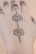 Intricate henna or mehndi design adorns the top of a hand, featuring floral patterns connected by a series of dots. The design extends over several fingers, with symmetrical details enhancing its aesthetic appeal.