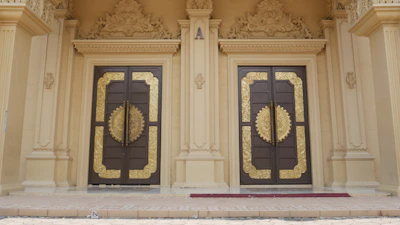 A grand entrance of a Bangalore villa showcasing classic luxury with gold-trimmed doors and refined landscaping.