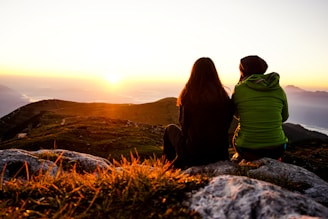 two women sitting on rock boulder