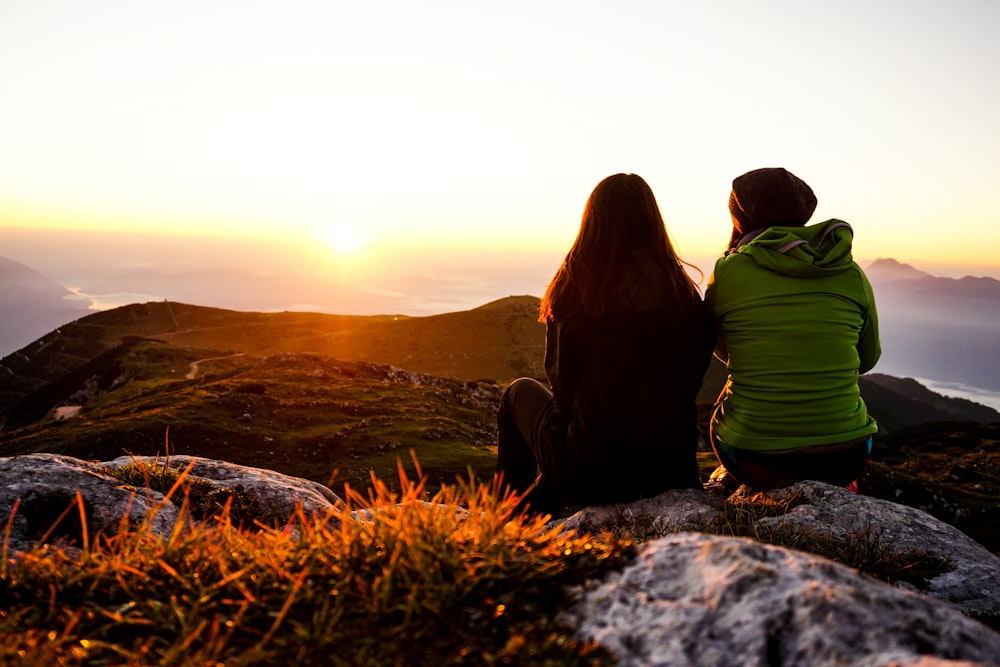 two women sitting on rock boulder