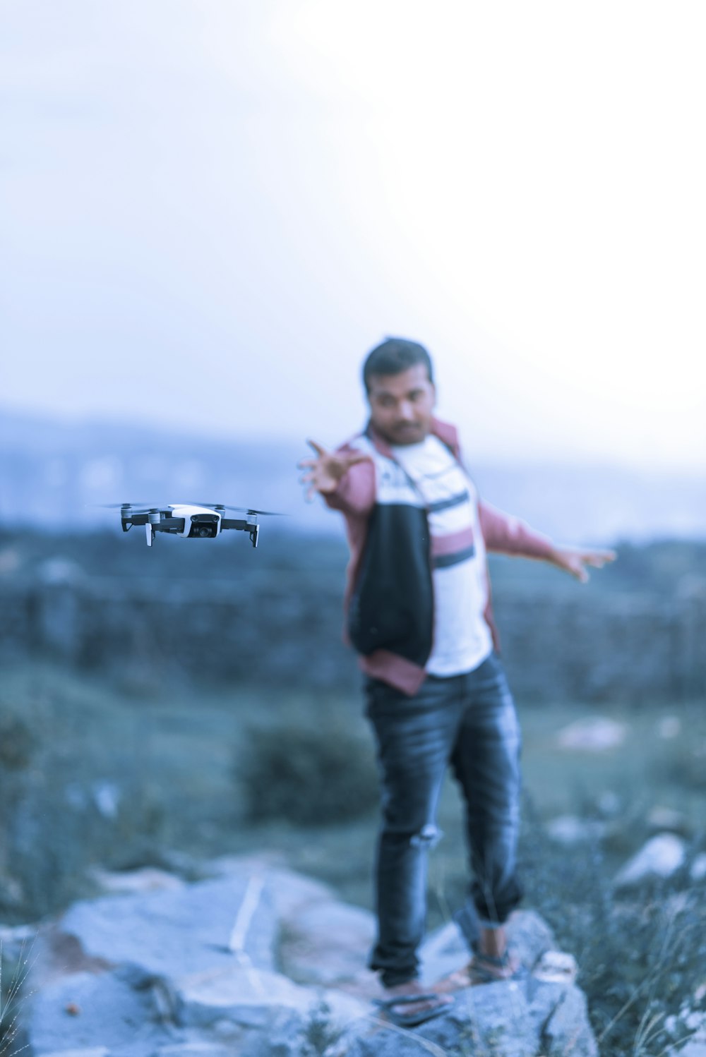 a man standing on top of a rock next to a remote control plane