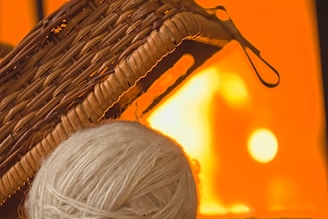 Handmade crochet basket filled with colorful yarn balls beside a softly lit workspace.