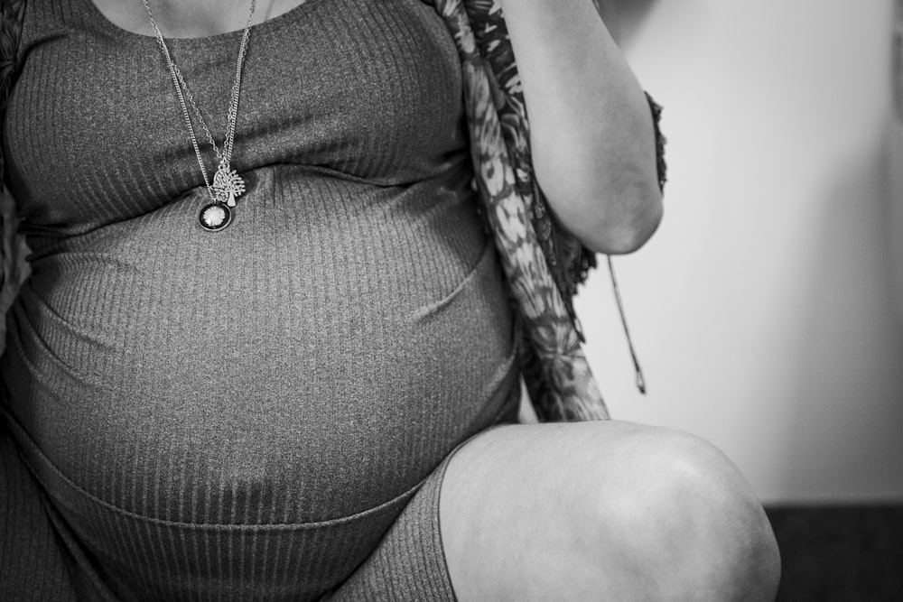 a pregnant woman sitting on a chair holding a cell phone to her ear