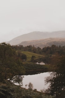 A serene landscape featuring a tranquil lake surrounded by misty mountains at sunrise.