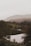 A serene landscape featuring a tranquil lake surrounded by lush greenery and mountains in the background.