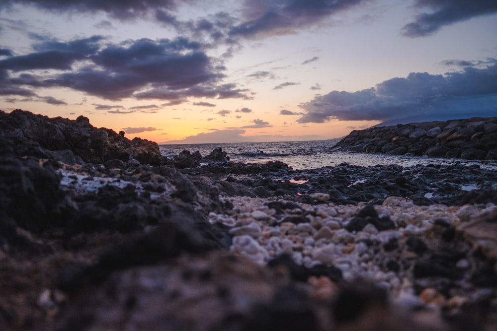 Il sole sta tramontando su una spiaggia rocciosa