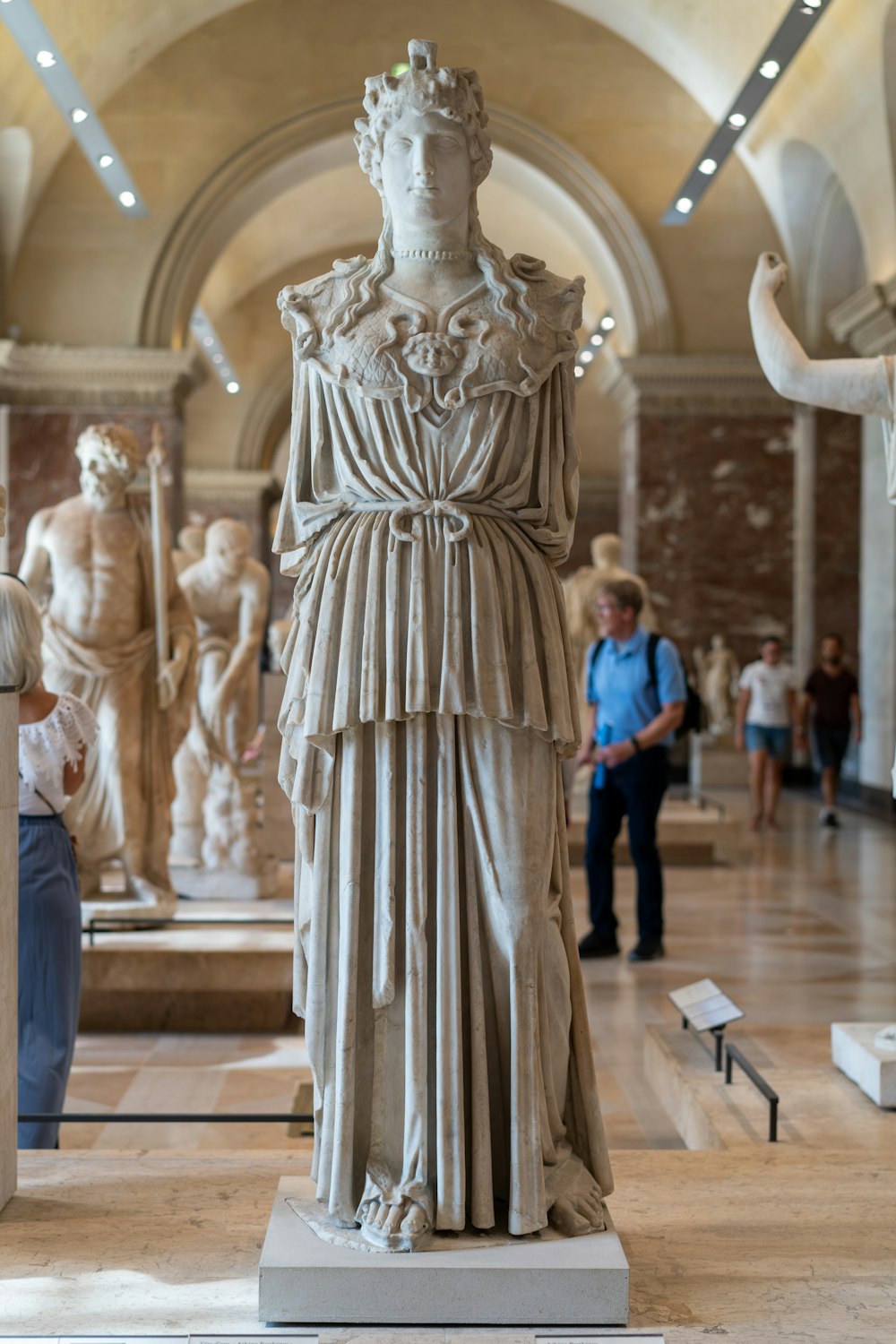 people walking beside marble statue of woman