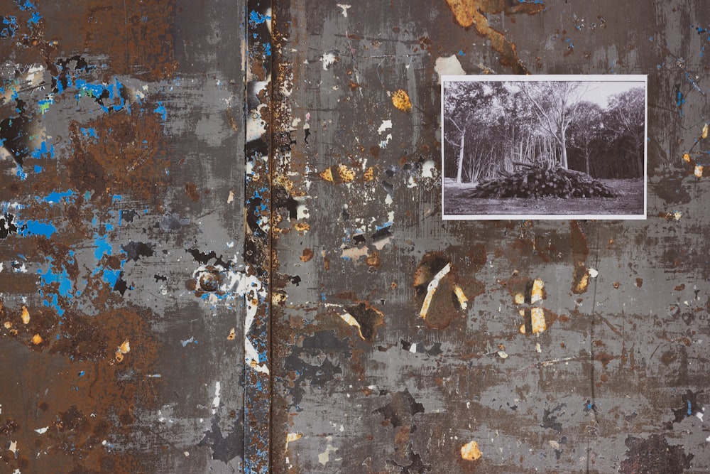 a rusted metal wall with a picture of trees on it