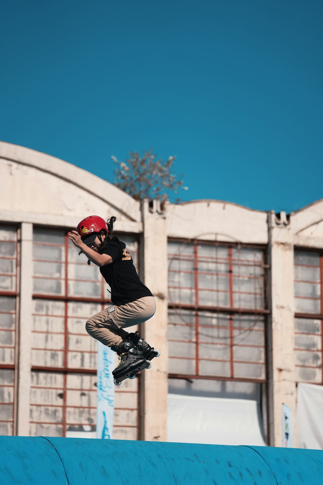 woman wearing black shirt and beige pants doing trick midair