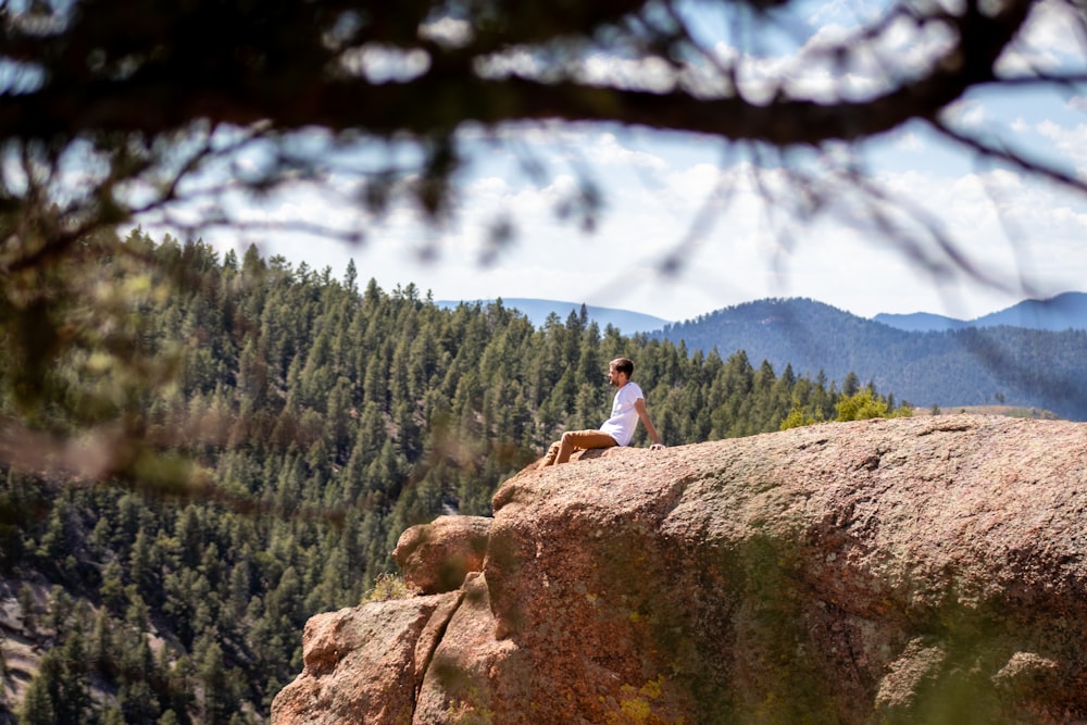 man sitting near rock cliff