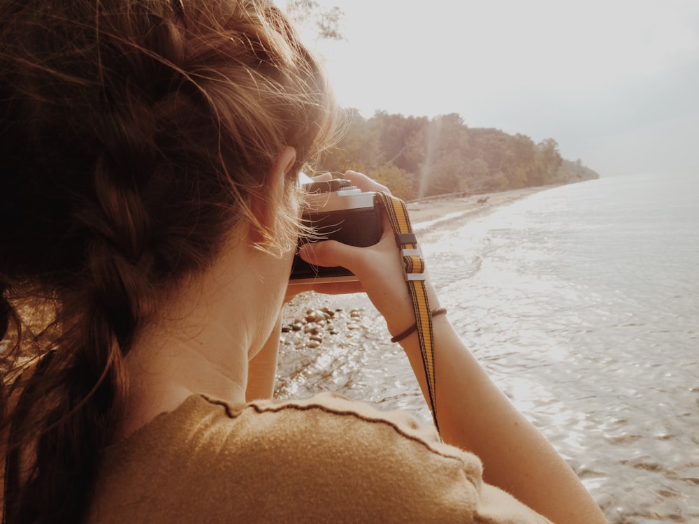 mulher tirando foto da costa e árvores
